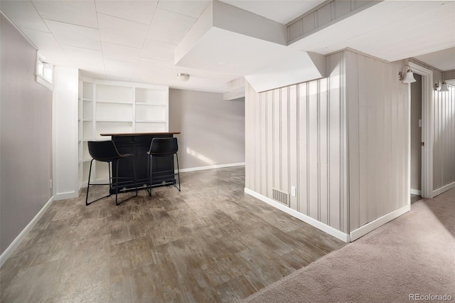 living area featuring wood finished floors, a dry bar, baseboards, and visible vents