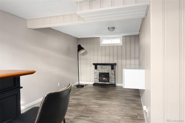 interior space with a stone fireplace, baseboards, and wood finished floors