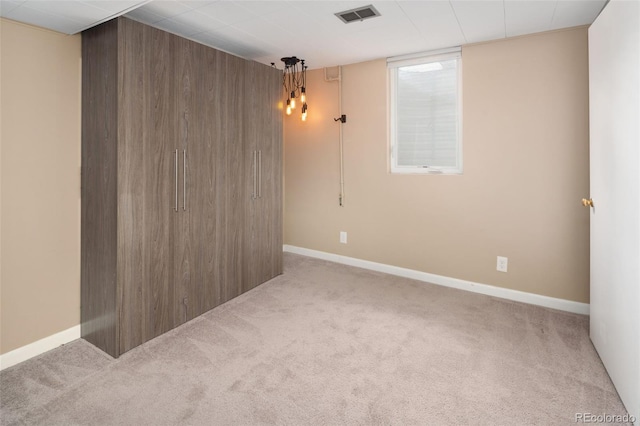 carpeted spare room featuring visible vents, baseboards, and wooden walls