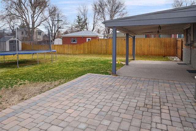 view of patio featuring a fenced backyard, a shed, an outdoor structure, and a trampoline