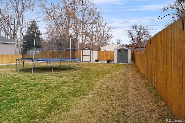 view of yard featuring a storage shed, a trampoline, a fenced backyard, and an outdoor structure