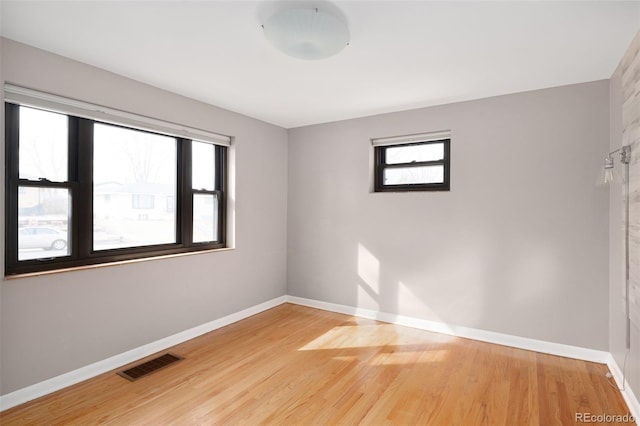 spare room featuring visible vents, plenty of natural light, light wood-style floors, and baseboards