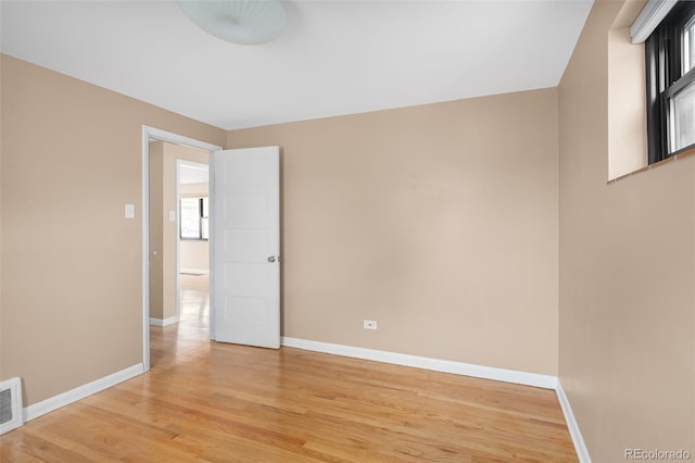 unfurnished room with visible vents, light wood-style floors, and baseboards