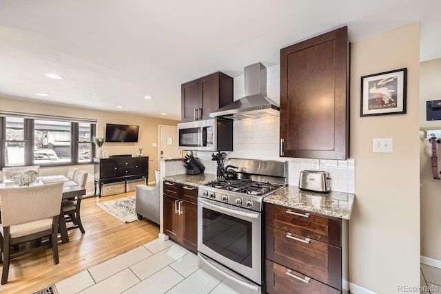 424 S Leyden St, Denver, CO 80224 - kitchen with appliances with stainless steel finishes, wall chimney range hood, dark brown cabinetry, tasteful backsplash, and light stone countertops