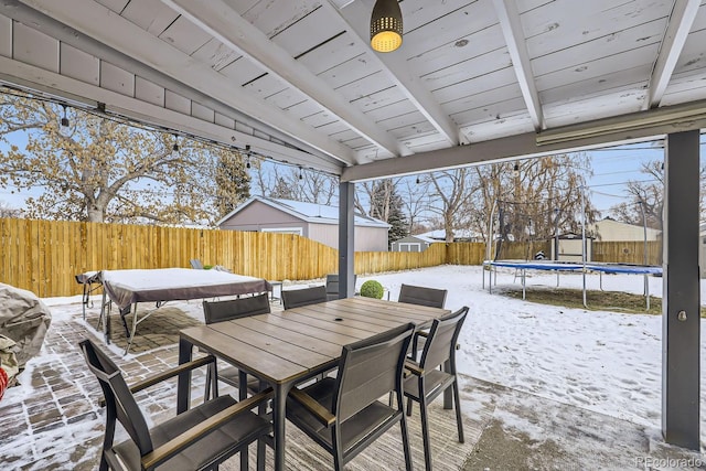 424 S Leyden St, Denver, CO 80224 - snow covered patio featuring a trampoline, outdoor dining area, and a fenced backyard