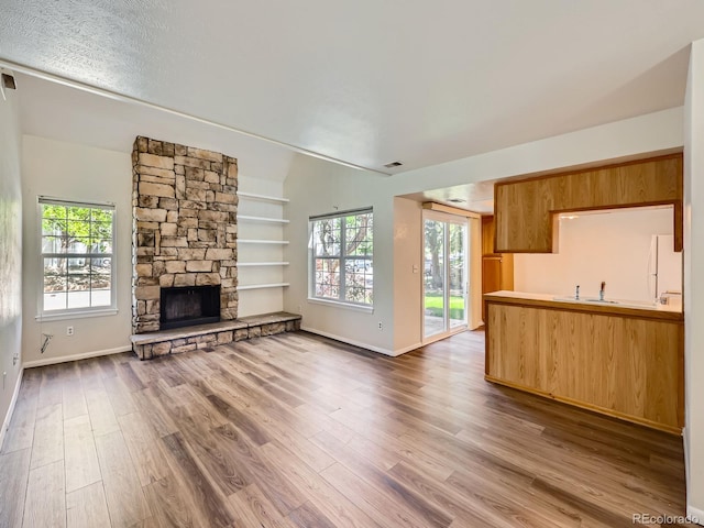 13598 E Asbury Dr, Aurora, CO 80014 - unfurnished living room featuring plenty of natural light, wood finished floors, a stone fireplace, and baseboards