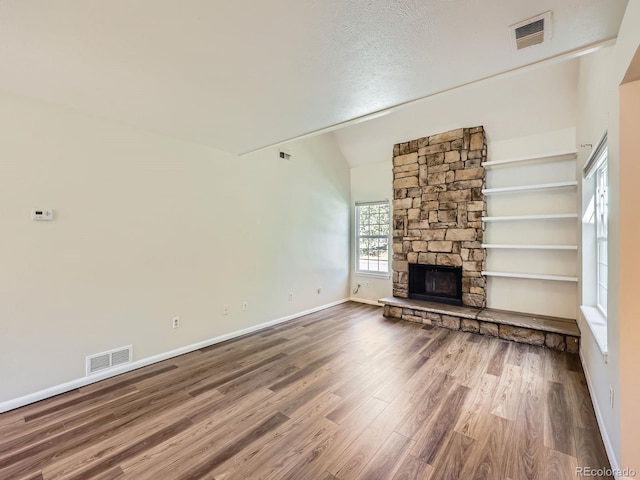13598 E Asbury Dr, Aurora, CO 80014 - unfurnished living room with wood finished floors, baseboards, a stone fireplace, and vaulted ceiling