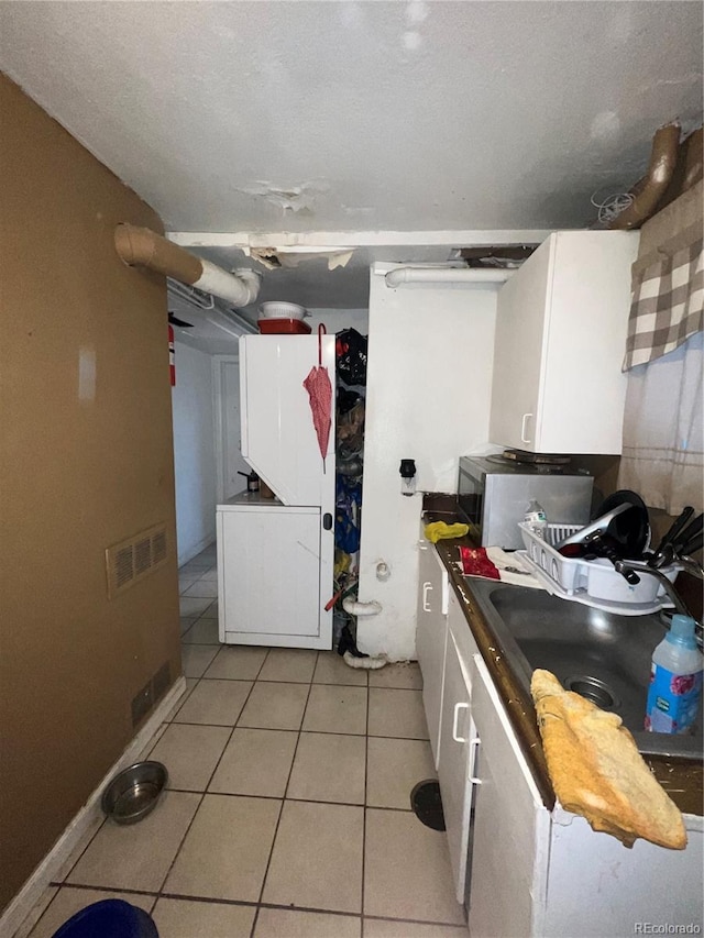 kitchen with white cabinets, a textured ceiling, and light tile patterned floors