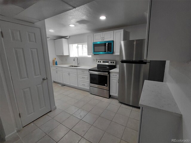 274 S Meade St, Denver, CO 80219 - kitchen featuring stainless steel appliances, a sink, light countertops, white cabinets, and a textured ceiling
