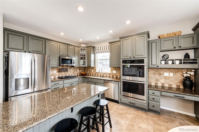 5550 Fox Meadow Ave, Highlands Ranch, CO 80130 - kitchen with stainless steel appliances, gray cabinetry, a breakfast bar area, dark stone countertops, and backsplash