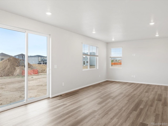 spare room featuring wood finished floors, recessed lighting, and baseboards