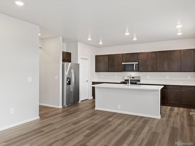 kitchen with appliances with stainless steel finishes, wood finished floors, recessed lighting, light countertops, and baseboards