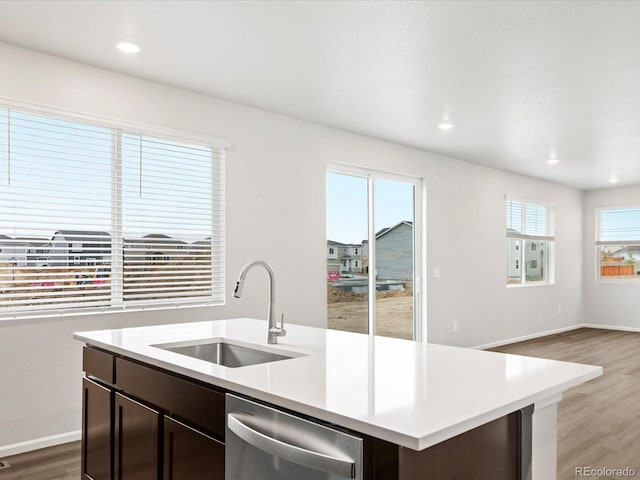 kitchen featuring a sink, dishwasher, dark brown cabinetry, light wood-style floors, and light countertops