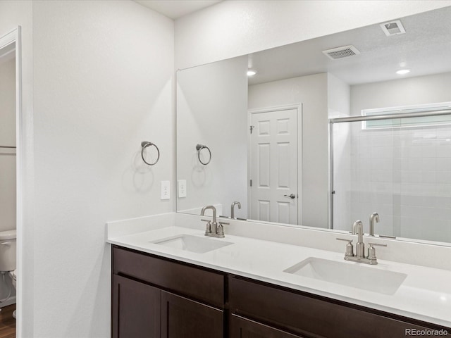 full bathroom featuring toilet, a shower stall, and double vanity