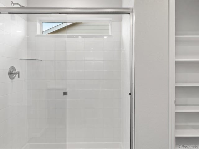 bathroom with a stall shower and a walk in closet
