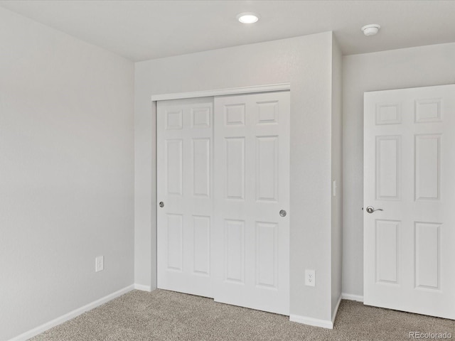 unfurnished bedroom featuring carpet flooring, baseboards, a closet, and recessed lighting