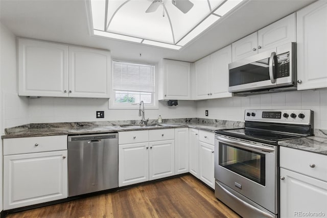 kitchen featuring stainless steel appliances, a sink, a ceiling fan, dark wood-style flooring, and stone countertops