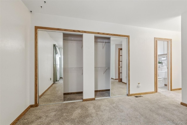 unfurnished bedroom with carpet flooring, baseboards, and ensuite bath