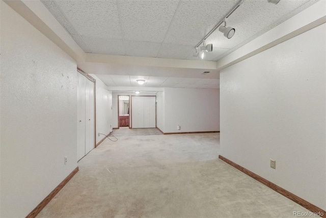 empty room with carpet, baseboards, and rail lighting