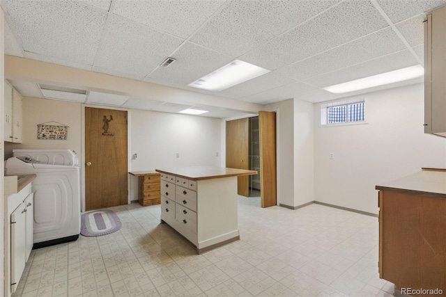 kitchen featuring washer / clothes dryer, a paneled ceiling, a kitchen island, and light floors