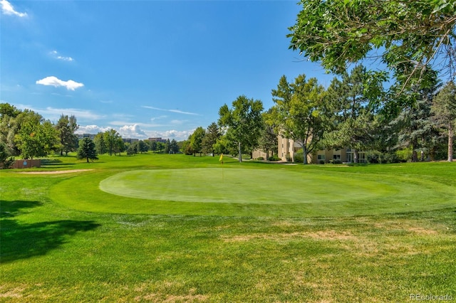 view of property's community featuring golf course view, a lawn, and view of scattered trees