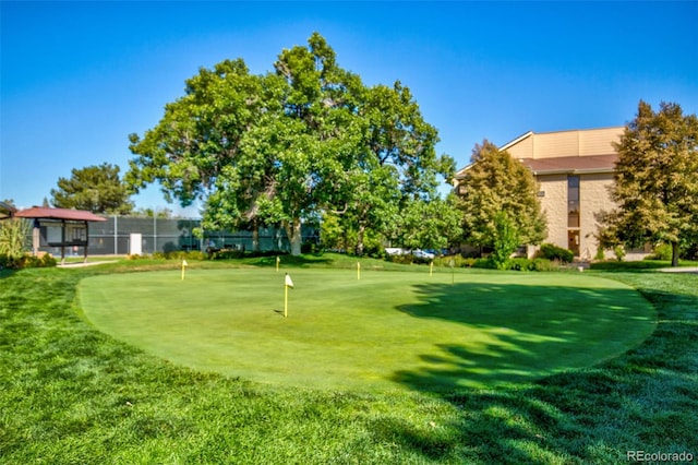 view of community featuring an area to practice putting and a lawn
