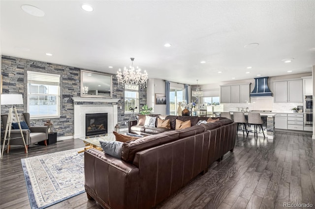 living room featuring dark wood-type flooring, a chandelier, and a fireplace