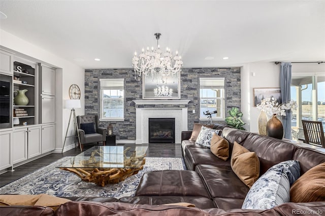 living room featuring a chandelier, dark hardwood / wood-style floors, and a stone fireplace