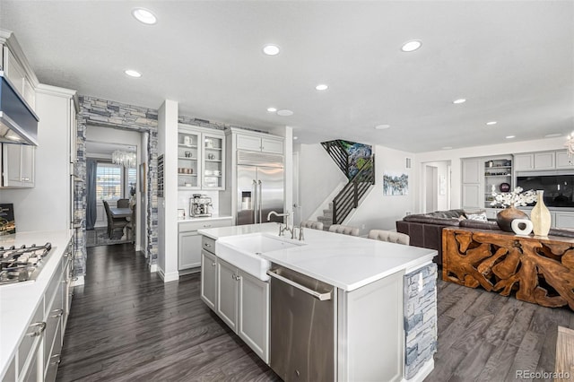 kitchen with dark hardwood / wood-style floors, sink, white cabinetry, a kitchen island with sink, and stainless steel appliances