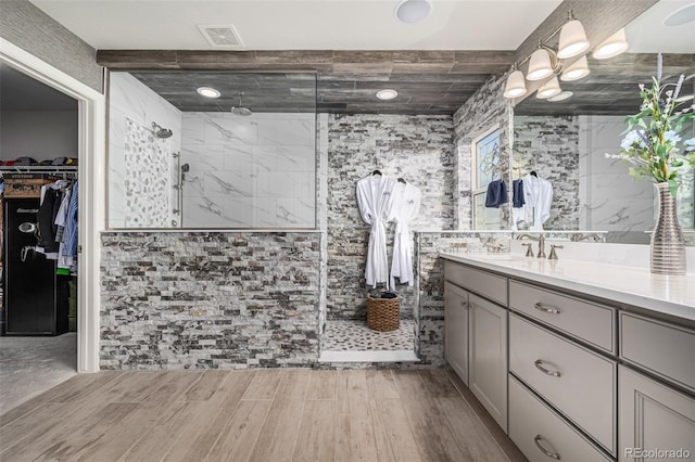 bathroom with tile walls, vanity, and a tile shower