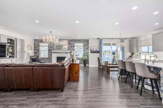 living room featuring dark hardwood / wood-style flooring, a notable chandelier, sink, and a large fireplace