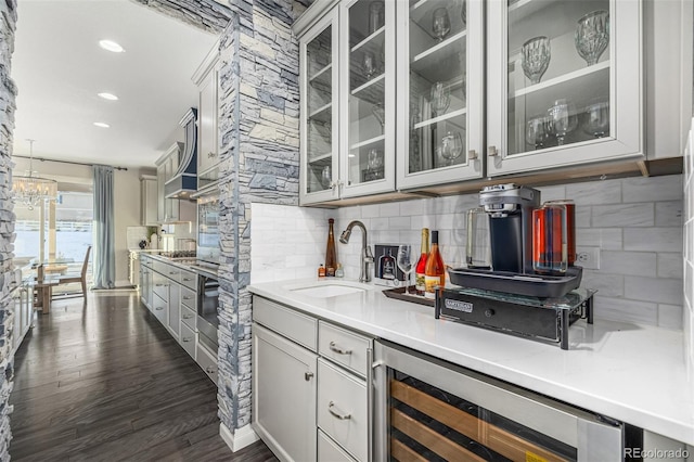 kitchen featuring dark wood-type flooring, sink, white cabinetry, beverage cooler, and backsplash