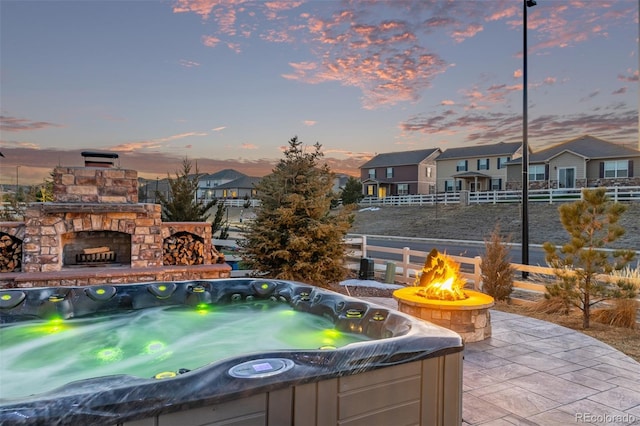 patio terrace at dusk with a hot tub and an outdoor fire pit