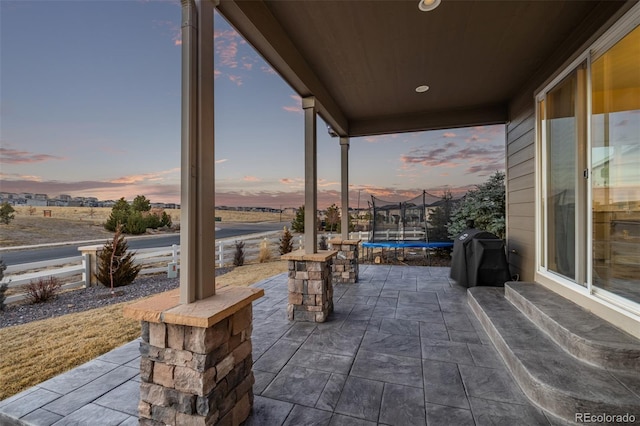 patio terrace at dusk with a trampoline and area for grilling