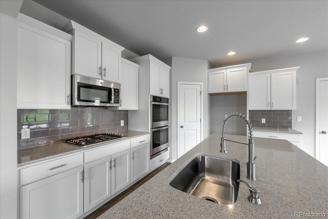 1711 Lazear St, Loveland, CO 80538 - kitchen with appliances with stainless steel finishes, a sink, white cabinets, recessed lighting, and backsplash