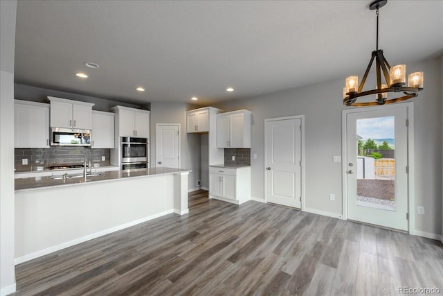 1711 Lazear St, Loveland, CO 80538 - kitchen with stainless steel appliances, a chandelier, backsplash, wood finished floors, and white cabinets