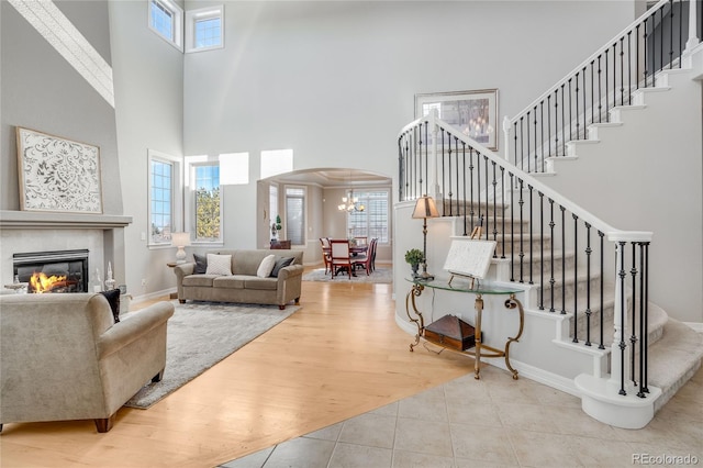 living room with a chandelier, light wood-type flooring, a high ceiling, and a wealth of natural light