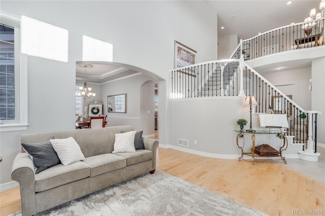 living room with a high ceiling, wood-type flooring, crown molding, and a chandelier