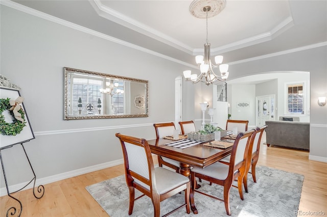 dining area featuring crown molding, light hardwood / wood-style floors, an inviting chandelier, and a tray ceiling