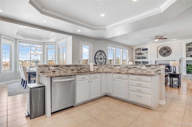 kitchen featuring a raised ceiling, light stone countertops, stainless steel dishwasher, and white cabinets