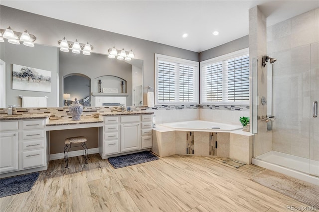 bathroom featuring wood-type flooring, separate shower and tub, and vanity