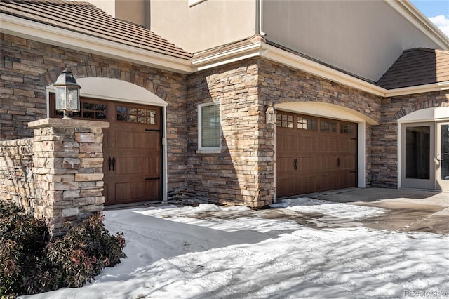 snow covered property entrance featuring a garage