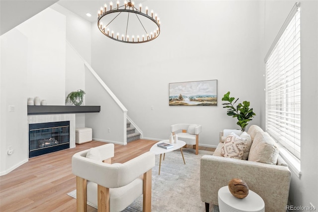 living room featuring a tiled fireplace, a towering ceiling, and hardwood / wood-style flooring