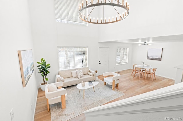 living room featuring an inviting chandelier, hardwood / wood-style floors, and a towering ceiling