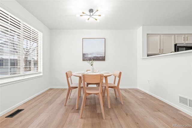 dining room with light hardwood / wood-style flooring and a notable chandelier