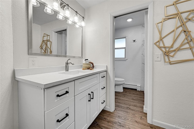 7076 S Spruce Dr W, Centennial, CO 80112 - bathroom featuring a baseboard radiator, toilet, wood finished floors, vanity, and baseboards