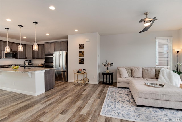 living room with wood-type flooring, ceiling fan, and sink