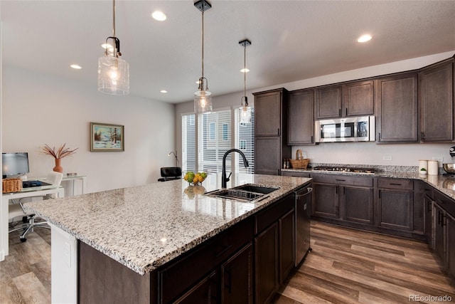 kitchen with appliances with stainless steel finishes, sink, decorative light fixtures, and an island with sink