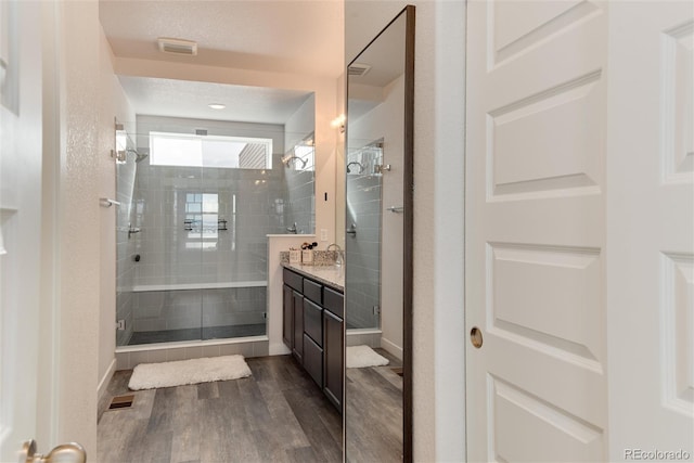 bathroom featuring wood-type flooring, vanity, a textured ceiling, and a shower with shower door