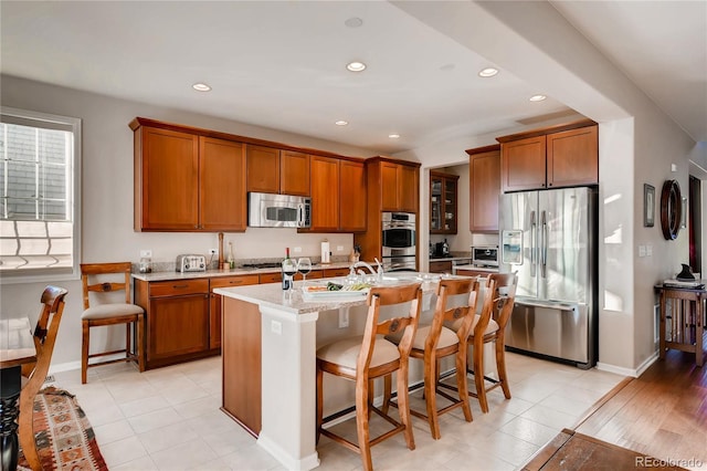 kitchen with recessed lighting, appliances with stainless steel finishes, a breakfast bar area, and brown cabinets